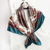 A silk print shawl featuring brown, gold, and teal patterns tied around a white shirt.