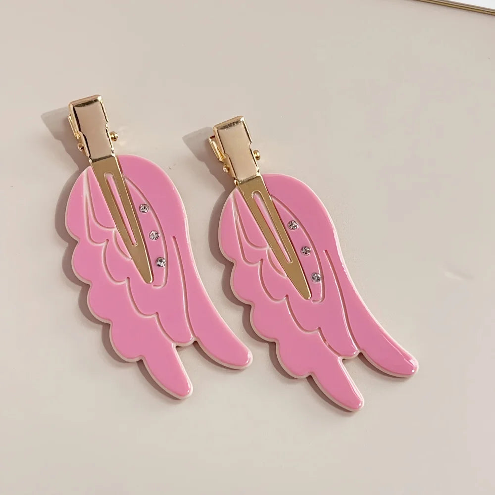 Pair of pink angel wing hair clips with gold-toned barrettes and small rhinestones