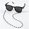 Black sunglasses with a chain of small black beads hanging from the arm.
