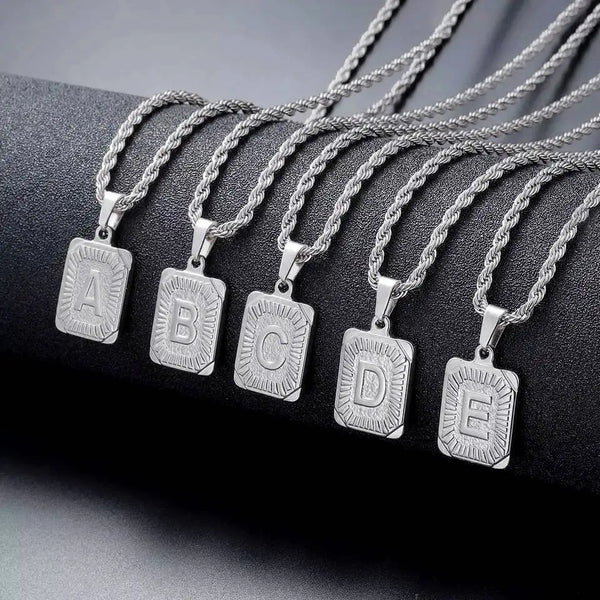 A set of five silver letter pendant necklaces labeled A through E displayed on a black surface.