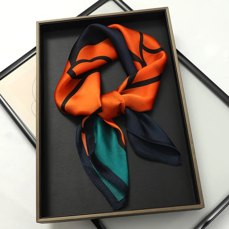 An orange and navy silk scarf tied in a bow displayed in a black rectangular frame.