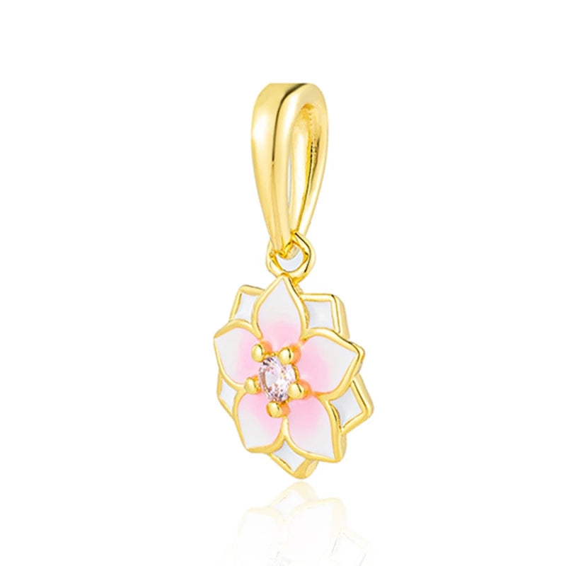Un dije de color dorado con forma de flor rosa y blanca y una piedra central transparente.