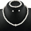 A necklace and matching earrings set of faux pearls displayed on a black display stand.