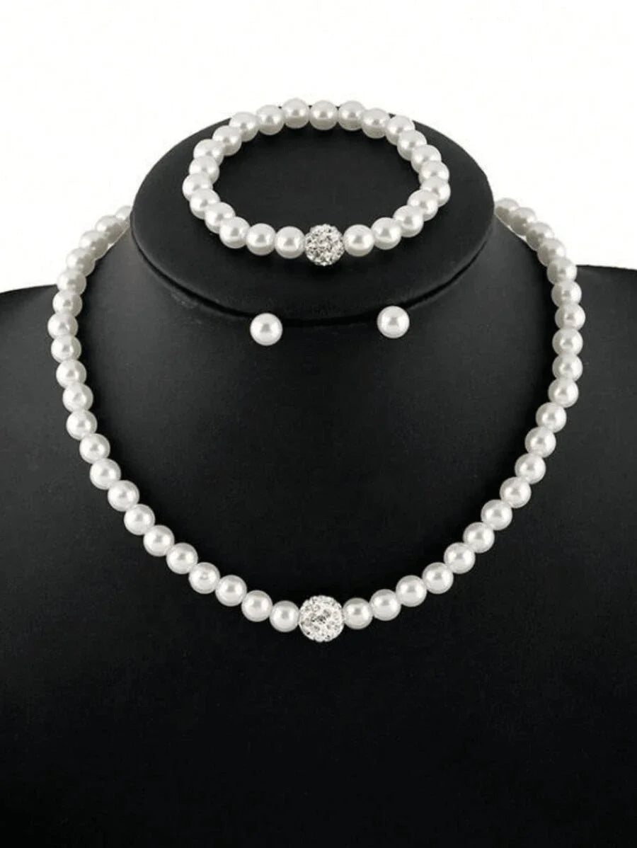 A necklace and matching earrings set of faux pearls displayed on a black display stand.