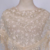 A sheer beige floral lace scarf draped over a mannequin neck.
