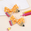 A set of orange and pink pencil bow hair clips displayed on a light background.