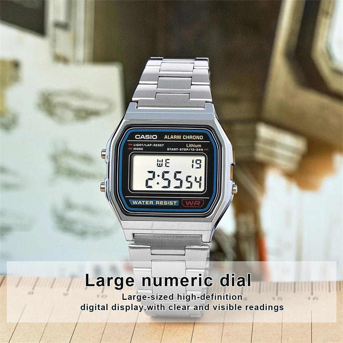 A silver Casio Alarm Chrono watch with a large numeric dial and metal bracelet displayed on a wooden surface.