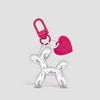 A silver cartoon dog keychain with a pink heart charm and a pink carabiner clip.