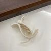 A white acrylic hair claw designed for ponytail styling, shown against a light surface.