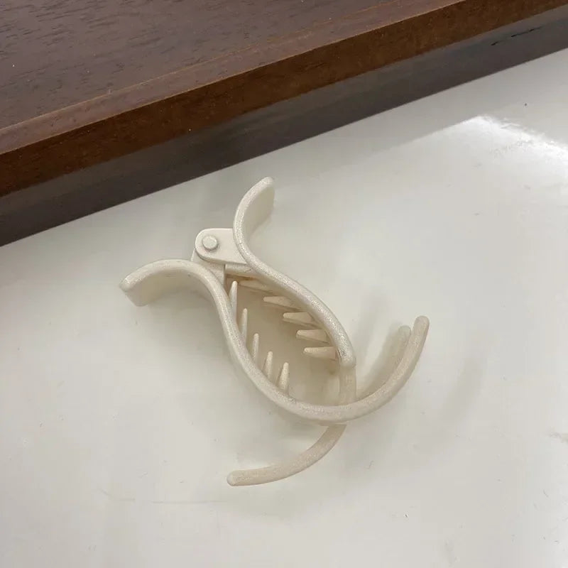 A white acrylic hair claw designed for ponytail styling, shown against a light surface.