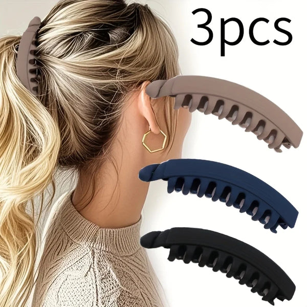 Three large banana hair clips in brown, navy blue, and black shown against a woman's hair.