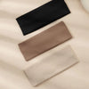 A pack of three solid color fashion headbands in black, brown, and beige laid diagonally on a light fabric background.