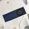 Navy blue polka dot fabric headband with a black button closure on a white background.