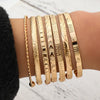 A set of elegant gold bangles featuring hexagon and star patterns worn on a person's wrist.