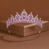 A sparkling purple crystal baroque bridal tiara headpiece resting on a brown box.