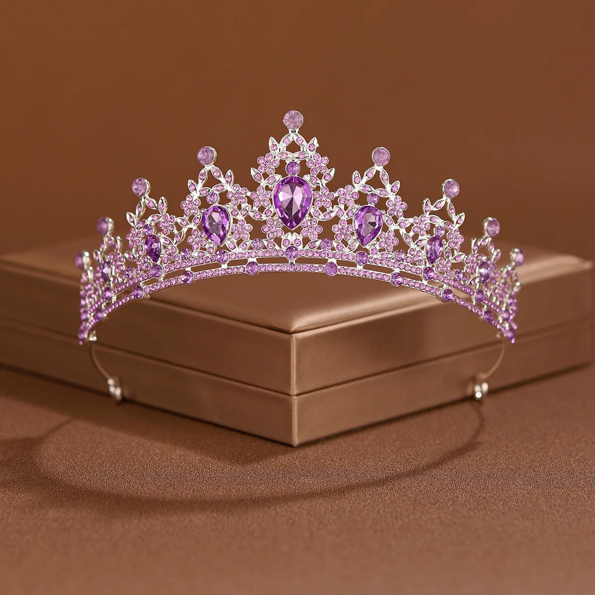 A sparkling purple crystal baroque bridal tiara headpiece resting on a brown box.