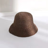 A close-up view of a brown hand-woven straw visor hat resting on a white surface.