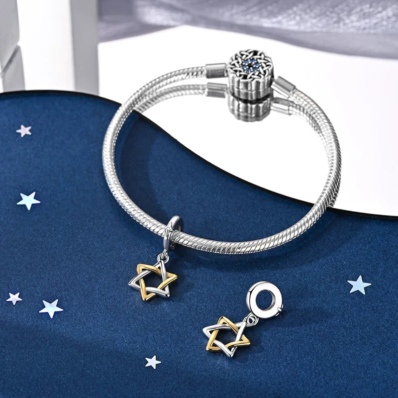 Sterling silver star moon charm bracelet displayed on a dark blue fabric with white stars