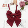 A deep burgundy solid cotton bow tie displayed on a white background with floral and natural textures.