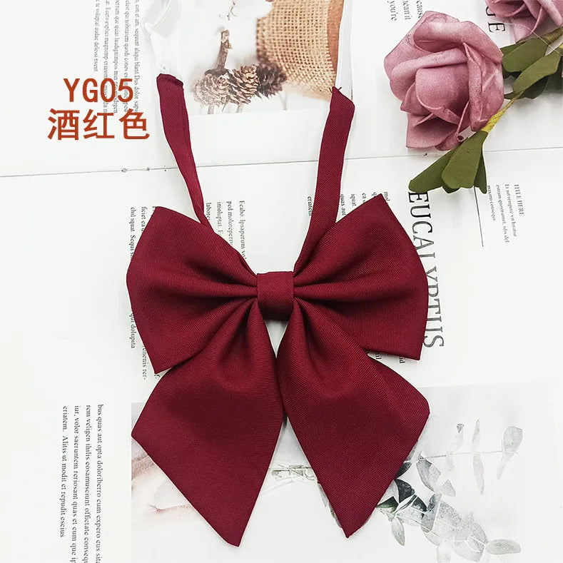 A deep burgundy solid cotton bow tie displayed on a white background with floral and natural textures.