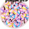 A bowl filled with 10 pieces of colorful, striped resin nail art charms in pink, blue, and yellow.