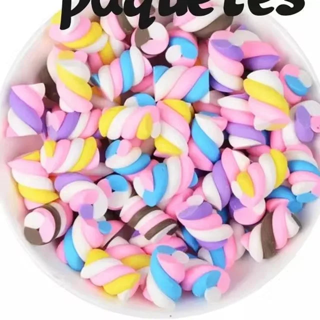 A bowl filled with 10 pieces of colorful, striped resin nail art charms in pink, blue, and yellow.