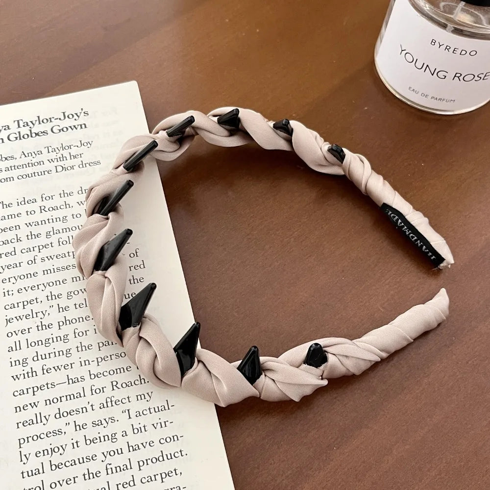 A beige knotted hair headband with black teeth is shown against a white magazine page.