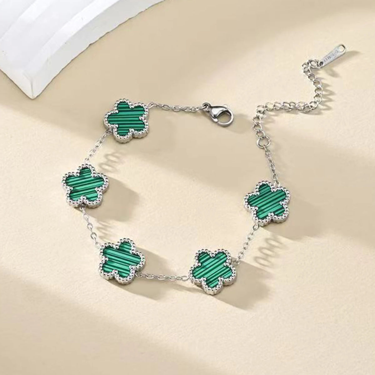 A silver gold plated stainless steel bracelet featuring multiple green enamel petals.