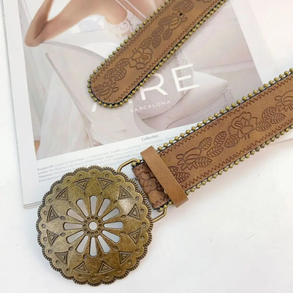 A brown vintage PU leather boho western belt with a gold circular buckle and embossed leather strap.