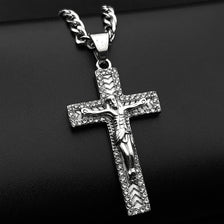 A silver-tone stainless steel cross pendant necklace with rhinestone accents displayed against a black background.