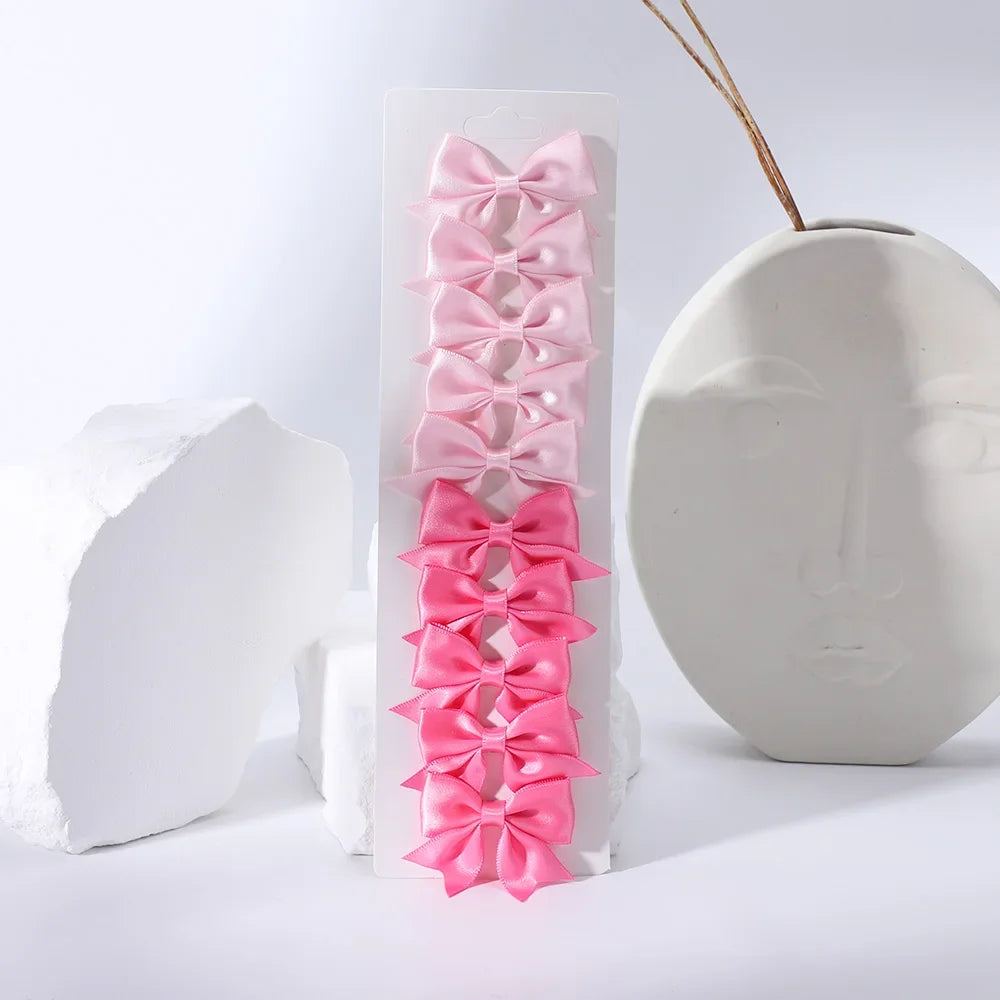 Pink satin ribbon bow hair clips displayed vertically against a white background.