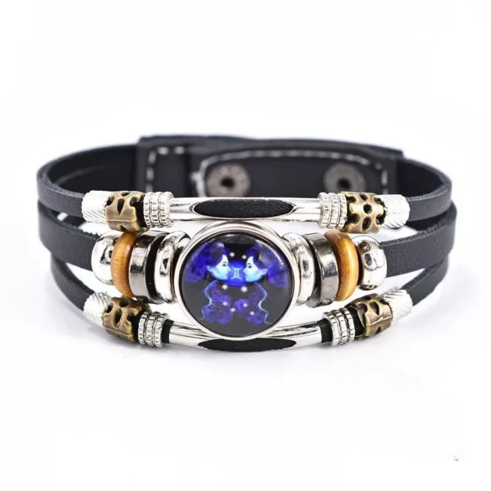 Schwarzes Lederarmband mit mehreren Lagen silberner Perlen und einem zentralen dunkelblauen Edelstein.