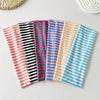Collection de bandeaux pour cheveux colorés et rayés disposés sur une surface claire.