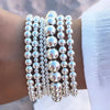A stack of silver-toned round beads forming a bracelet set worn on a wrist.