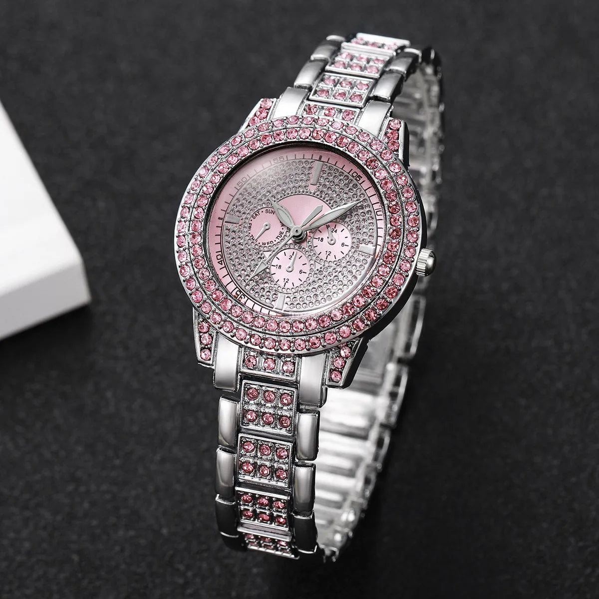 A silver watch with a pink diamond rhinestone bezel and a matching bracelet set on a dark background.