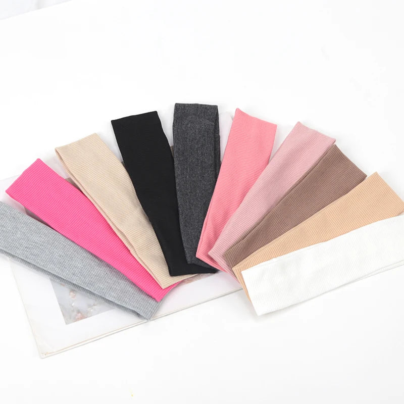 A collection of knitted elastic headbands in various shades including pink, black, gray, and beige.