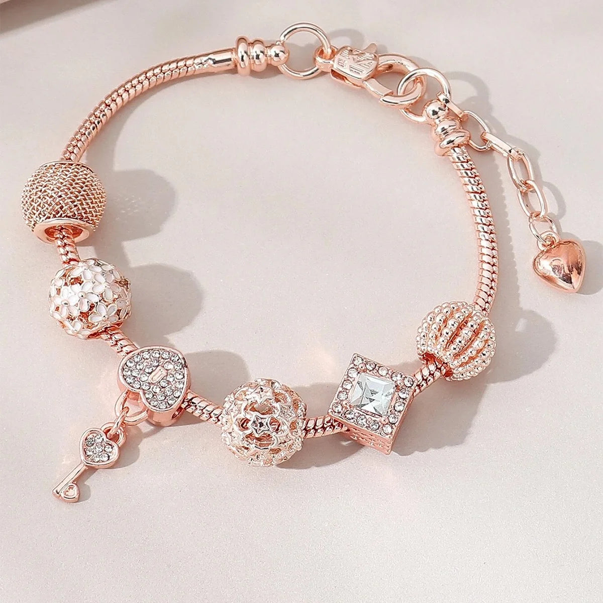 A delicate rose gold beaded bracelet set featuring various elements including spheres, hearts, and diamond-cut accents.