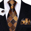 A close-up of a men's silk jacquard tie featuring a brown and gold checkered pattern worn with a black suit jacket.