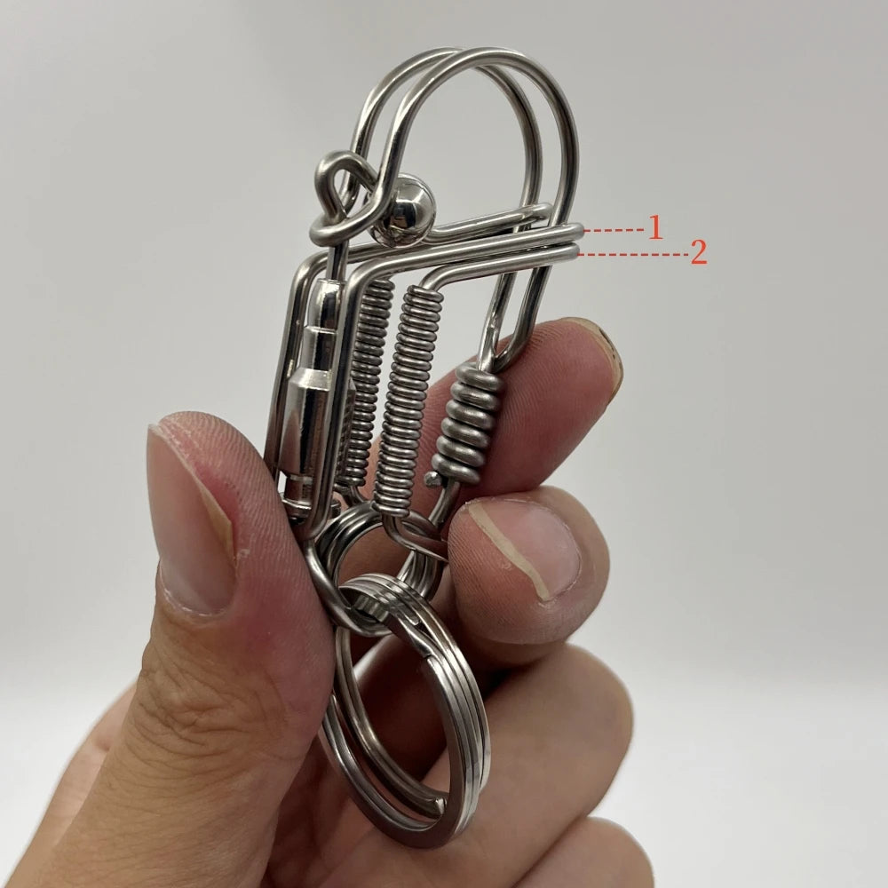 Une main tient une clé USB mécanique en acier inoxydable avec un ressort et une boucle circulaire.