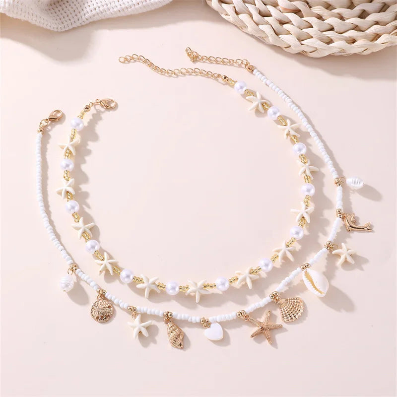 A delicate gold and white beaded necklace featuring starfish and shell charms.