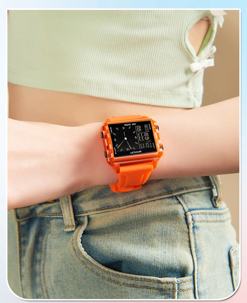 An orange digital wristwatch is worn on a person's wrist, visible against a light green top and denim jeans.