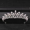 Silver crystal rhinestone bridal tiara headpiece with pearl drops displayed on a black surface.