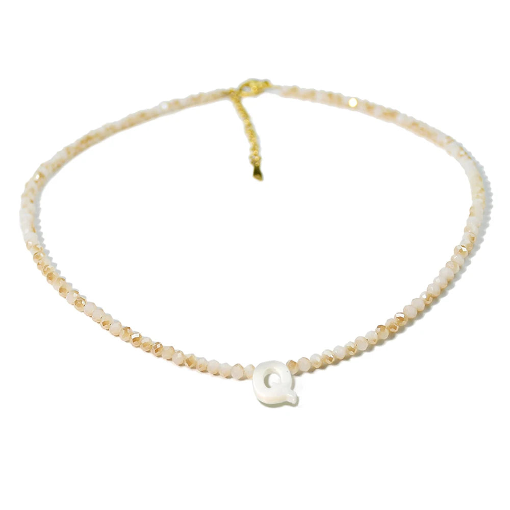 A delicate necklace made of mother of pearl beads with crystal accents and a gold-colored cord.