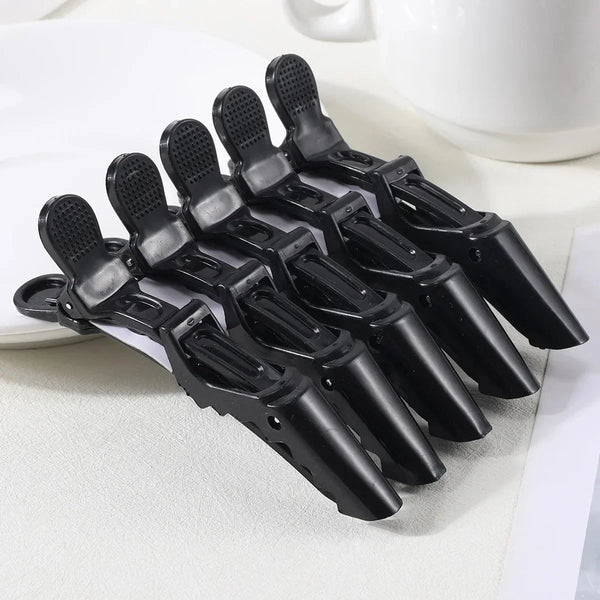 A pack of five black plastic hair styling clips arranged diagonally on a white surface.