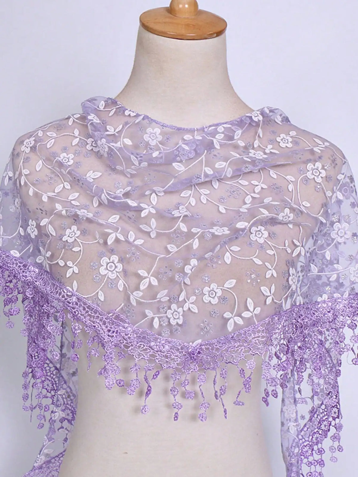 A sheer lavender floral lace scarf draped around a mannequin's neck.
