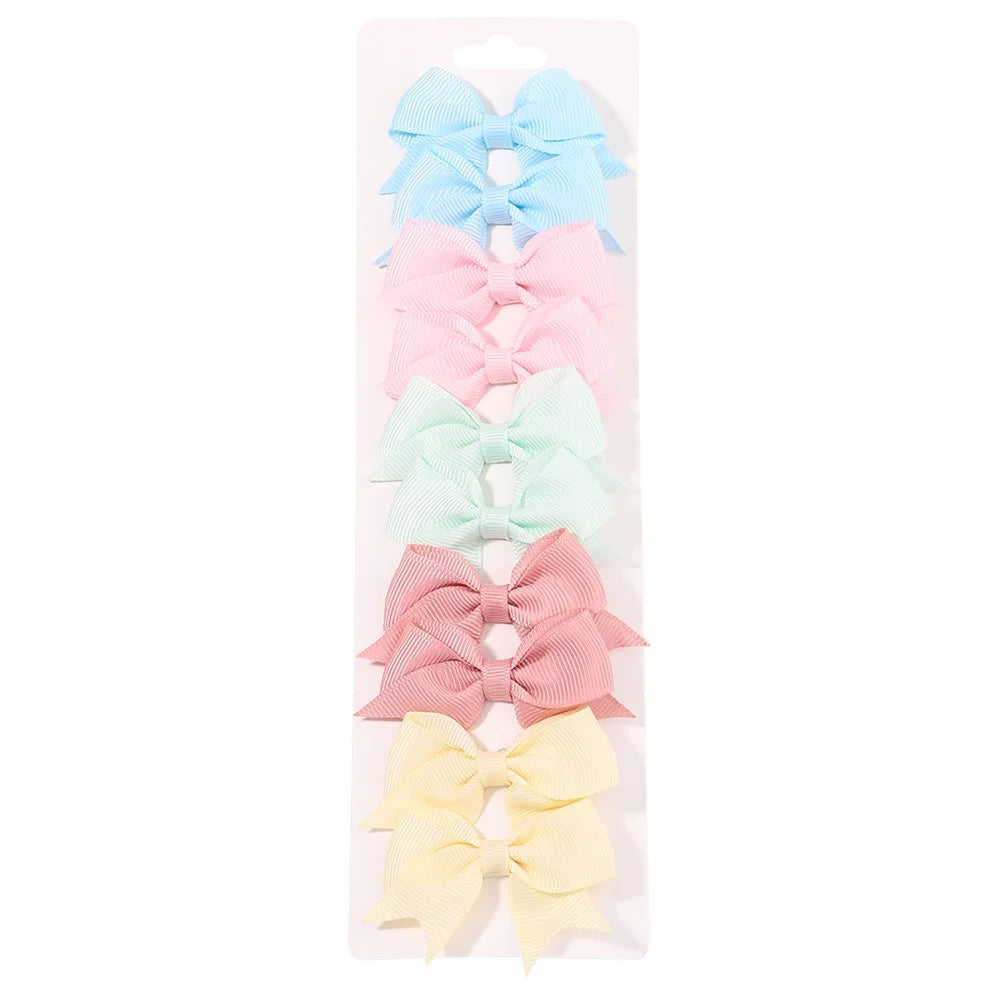 A collection of handmade ribbon bow hair clips in blue, pink, mint green, and yellow arranged in a packaging display.