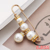 Gold-toned heavy duty pearl safety pins with clear accents displayed on a brown surface.