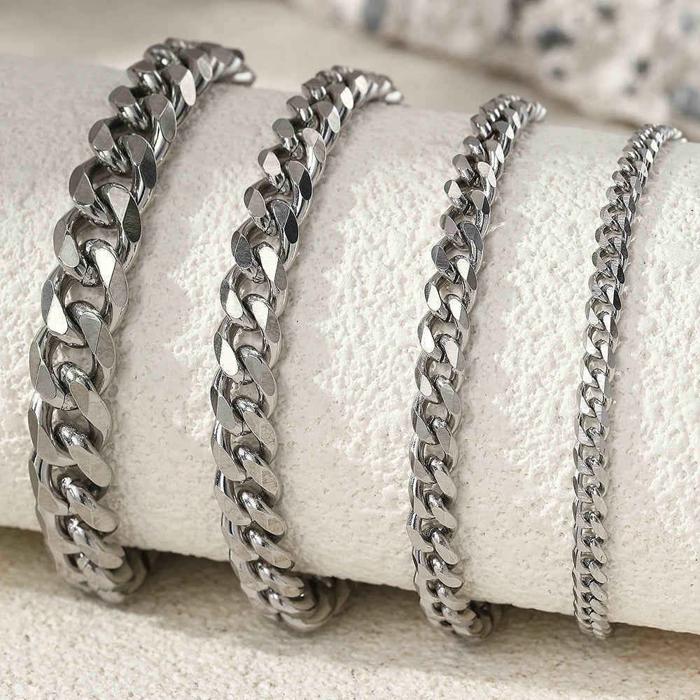 Silver multi-chain stainless steel anklets displayed on a white textured surface.