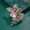 Broche florale en cristal élégante avec des pierres roses et vertes sur un support argenté.