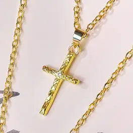 Collier pendentif de couleur or avec un design de lettre et de croix sur une chaîne.